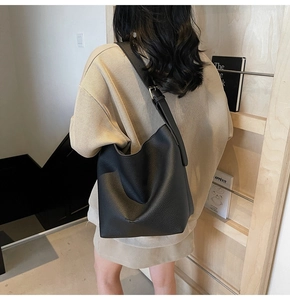 Détail d'un sac hobo en cuir noir avec bandoulière réglable porté à l'épaule