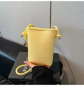 Dettaglio della borsa a secchiello in pelle gialla con cuore d'argento e logo SUNWOMEN