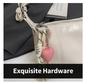 Close-up of cream glossy leather bag with silver metal ring and pink heart charm