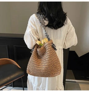 Detail of hand-woven straw tote bag with black and white twill strap and tulip accent