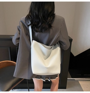 Détail du sac cabas en cuir blanc à motif litchi avec logo et large bandoulière souple