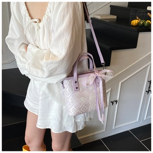Detail of light purple tote bag with white floral embroidery and delicate lace bow