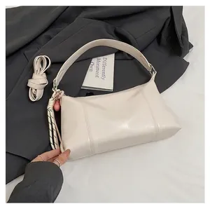 Detail of off-white leather shoulder bag with fine stitching and chic decorative pendants