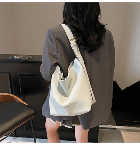 Détail du sac seau en cuir grainé blanc avec bandoulière large et boucle dorée