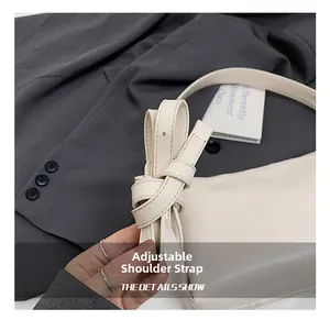 Detail of adjustable strap on beige leather shoulder bag with sleek hardware