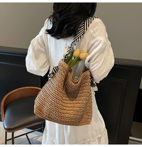 Detail of straw tote bag showing hollow weave texture and striped shoulder strap