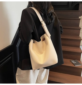 Détail du sac seau blanc crème en cuir grainé montrant la boucle dorée et le logo