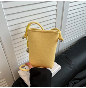 Dettaglio della mini borsa a secchiello in pelle gialla con logo SUNWOMEN in rilievo
