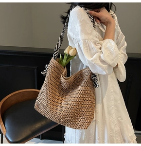 Detail of summer straw tote bag with black and white striped ribbon strap and side bow