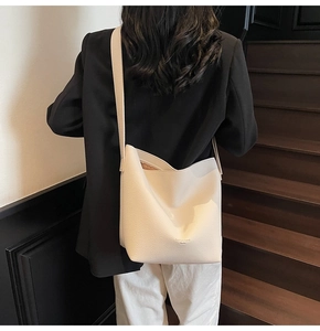 Vue détaillée du sac seau crème en cuir grainé avec une inscription dorée sur le sac