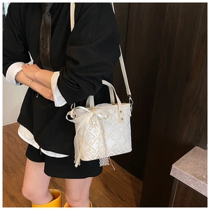 Detailed shot of an off-white lace handbag with bow accent and geometric floral pattern