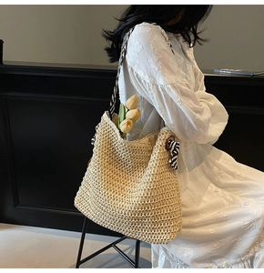 Detail of hand-woven straw tote bag with zebra print strap and ribbon bow accent
