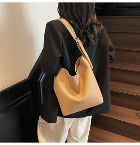 Détail du sac seau en cuir grainé avec bandoulière large réglable et boucle métal