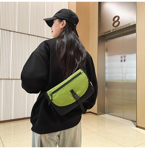 Dettaglio della borsa a tracolla verde neon a scacchi con fibbia nera su un modello