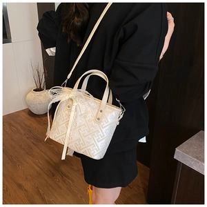 Detail of white bucket bag with geometric texture and delicate lace bow ribbon accessory
