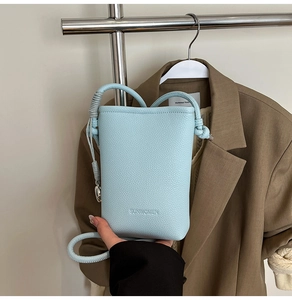 Dettaglio della borsa a secchiello celeste con motivo litchi e tracolla sottile