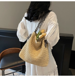 Detailed texture of handwoven straw tote with elegant black and white striped ribbon strap