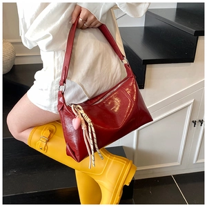 Detail of burgundy patent leather shoulder bag with trendy heart charm and metal zipper