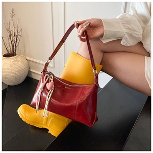 Detail of dark red baguette bag with leather texture and a cute heart charm accessory