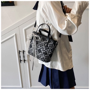 Detail of black embroidered bucket bag with lace bow and elegant geometric patterns