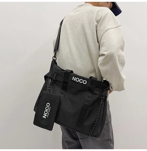 Rear view of model wearing a black nylon tote bag with white NOCO text logo