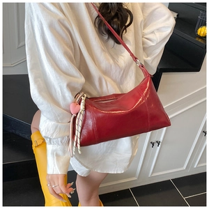 Model wearing a bright red rectangular shoulder bag with a pink heart charm