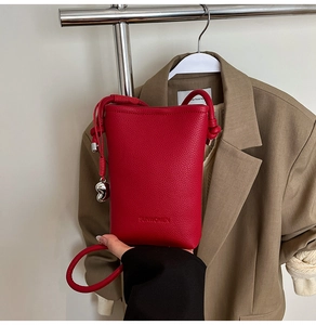 Dettaglio della borsa rossa in pelle a grana con logo SUNWOMEN e ciondolo cuore
