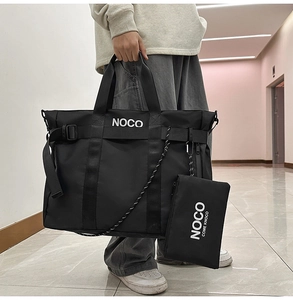 Detail of black nylon tote bag featuring white NOCO logo and matching accessory pouch