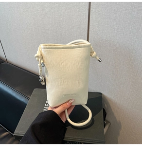 Dettaglio mini borsa a secchiello crema con trama litchi e ciondolo a cuore