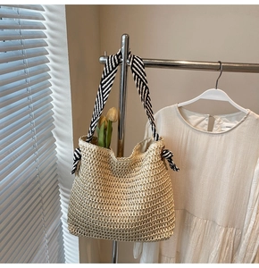Detail of oat straw woven tote featuring openwork knit and striped strap with bow