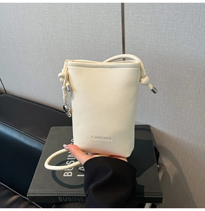 Dettaglio della borsa a secchiello bianco panna con texture litchi e logo SUNWOMEN inciso