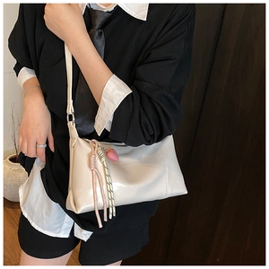 Detail of cream shoulder bag with woven rope knots and pink heart charm accessory