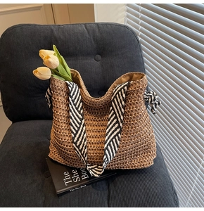 Detail of hand-woven straw tote bag with black and white striped ribbon bow handles