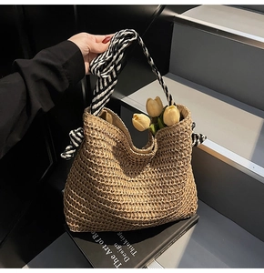 Close-up of woven straw tote bag with black and white striped bow and floral decor