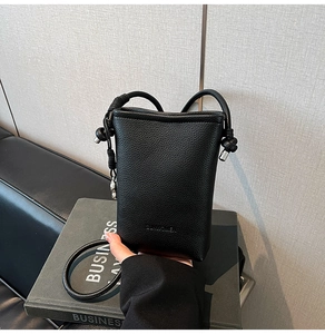 Dettaglio della pelle nera a grana e logo impresso sulla borsa a secchiello chic