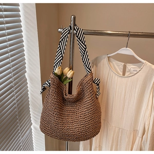 Detailed close-up of handmade straw tote bag with black and white striped shoulder strap