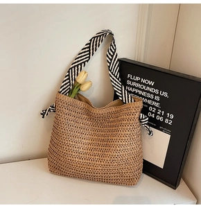 Detail of beige straw tote bag featuring contrast black and white striped canvas handles