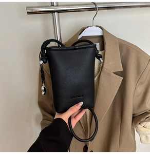 Dettaglio della mini borsa a tracolla in pelle nera a grana con logo in rilievo