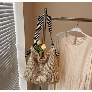 Detailed texture of handwoven straw tote with black and white striped ribbon handle