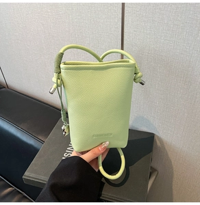 Dettaglio della borsa a secchiello in pelle litchi verde chiaro con logo SUNWOMEN