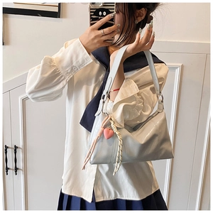Close-up of light blue patent leather shoulder bag with a pink heart pendant charm