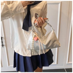 Close-up of silver patent leather shoulder bag featuring a 3D pink heart charm accessory
