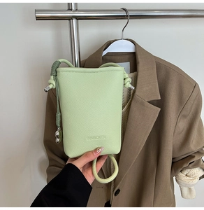 Dettaglio della borsa a secchiello in pelle litchi verde chiaro con logo SUNWOMEN inciso