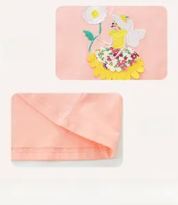 Détail de robe rose en coton montrant une broderie fée et des coutures soignées
