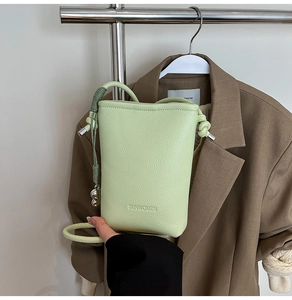 Dettaglio mini borsa a secchiello verde chiaro trama litchi con testo SUNWOMEN