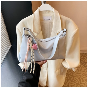 Close-up of light blue glossy handbag featuring a cute pink heart and striped rope charm