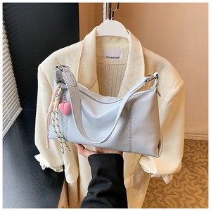 Light blue glossy leather shoulder bag featuring a pink heart charm and braided knot detail