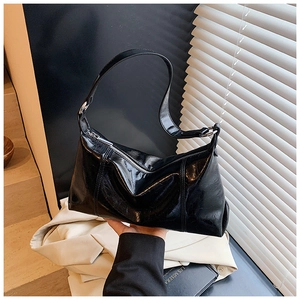 Detailed view of black wrinkled patent leather hobo bag with silver buckle and sleek zipper