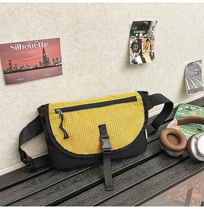 Dettaglio della borsa a tracolla in nylon giallo e nero con fibbia su una panca