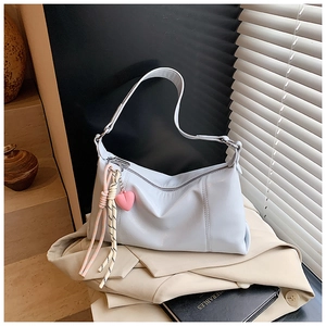 Close-up of light blue leather baguette bag with pink heart charm and tassel detail